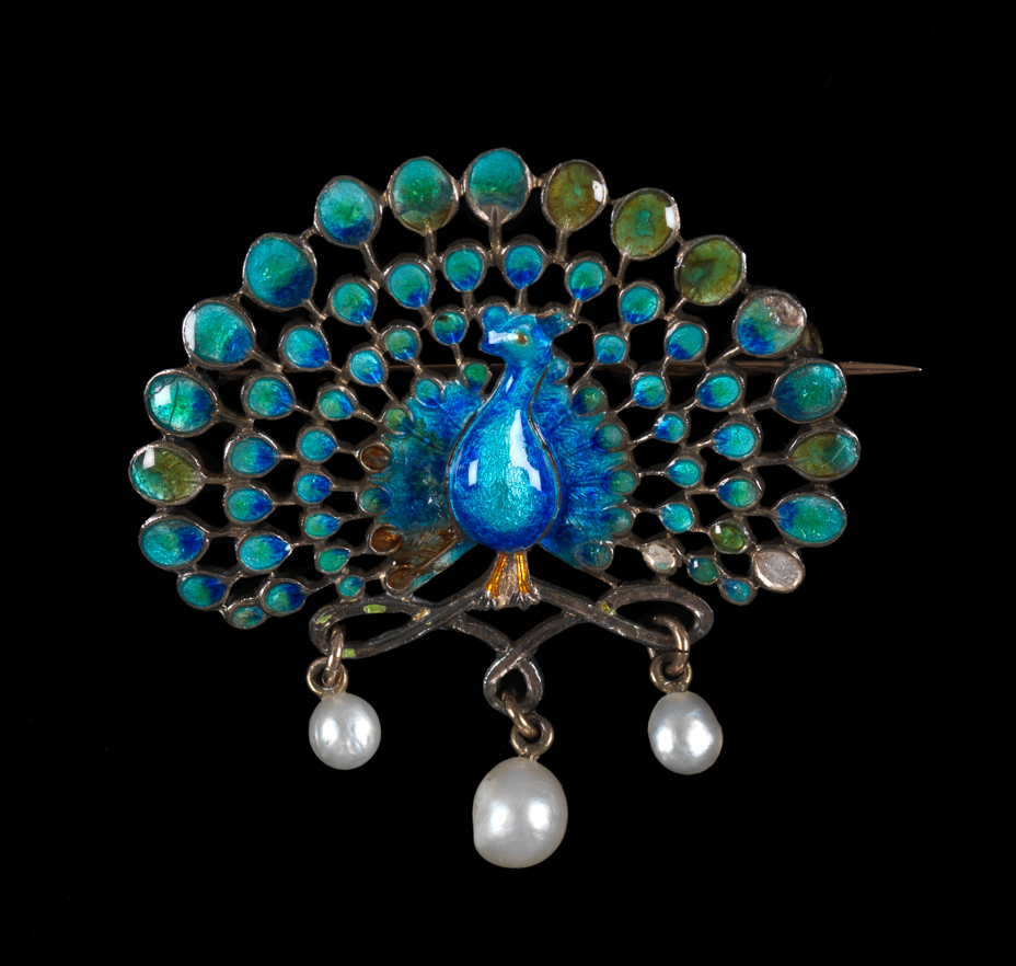 An image of Jewellery. Peacock brooch. Child & Child, London. In the shape of a peacock standing on three loops, from each of which is suspended a pearl drop. Pin-fastening across the back. In original dark turquoise leather case (A), lined with cream velvet and silk, the lid printed in gold 'CHILD & CHILD JEWELLERS/GOLD AND SILVERSMITHS/35 ALFRED PLACE WEST/QUEEN'S/GATE'. Gold, enamelled in blue, turquoise, yellow and green, with three pearl drops. Circa 1891-1899. Acquisition: given Mrs H. Hull Grundy.