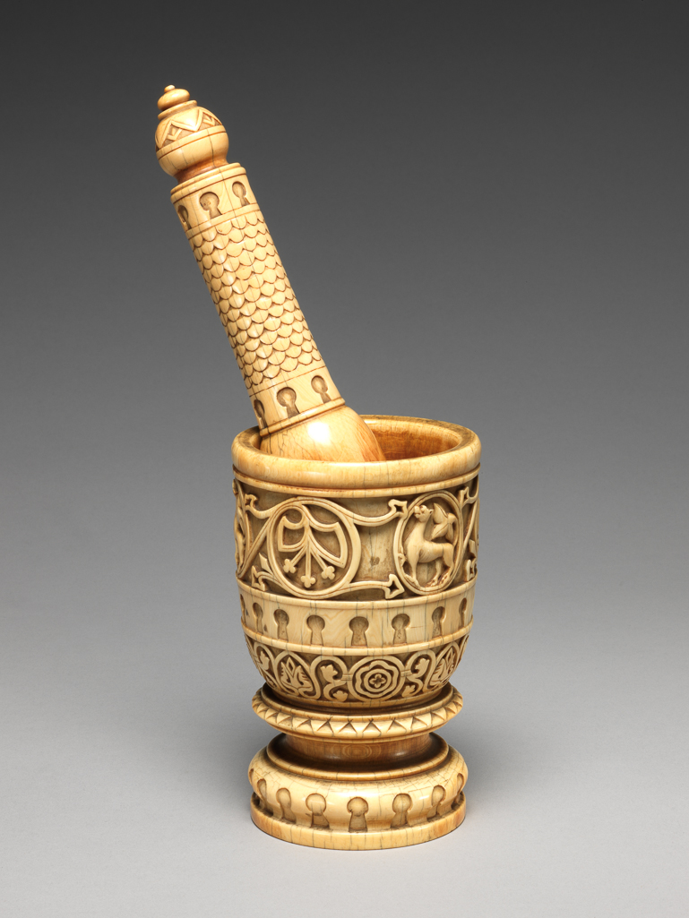 An image of Sculpture/ Pestle and mortar. The mortar is decorated with bands of ornament: a) at the top: a plain rim; b) a band of stylised foliated scroll-work with three medallions, each containing a fabulous beast with a foliated tail: c) a band of key-hole ornament; d) a band of stylised foliated scroll-work with four medallions, each containing a rosette. Around the thick short stem the mortar has several mouldings, including another band of key-hole pattern.The pestle handle is decorated with a scale pattern with a band (at the top and bottom) of key-hole pattern. A bulbous knob terminates the handle, and is carved with a triangular pattern. Ivory elaborately carved, height, pestle, 8.0 in, height, mortar, 5 1/4 in, diameter, mortar at top, 2 3/4 in, diameter, mortar at bottom, 2 7/8 in. Circa 1700-1800. Production Place: Sicily.