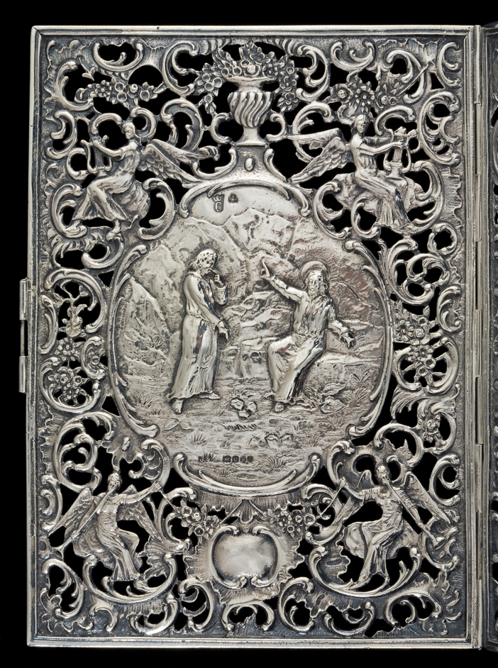 An image of Book cover/bible cover. Unknown silversmith, Netherlands or Germany. With two Biblical scenes amid openwork angels, urns, scrolls, diaper-work and flowers. The covers are rectangular, the spinge slightly concave and the clasp is shaped-triangular. The vignette on the front cover depicts St. John baptising Christ; the back cover possibly shows Christ risen from the tomb. They are surrounded by four angels playing musical instruments, amid vacant cartouches, urns, scrolls, diaper-work and flowers. The spine and clasp are similarly decorated with openwork scrolls. Silver, the hinged front and back cover, spine and clasp are cast and chased. Height, cover, 15.5 cm, width, cover, 11.2 cm, width, covers and spine, 25.8 cm, weight 260 g, 1880-1897. Notes: The book cover was accessioned as 18th century, but is probably late 19th century.The cover bears pseudo 16th or 17th Continental hallmarks, and English import marks for London 1897. Produced in Germany or The Netherlands but bearing English import marks for John George Smith & Co, who imported the cover into London in 1897.