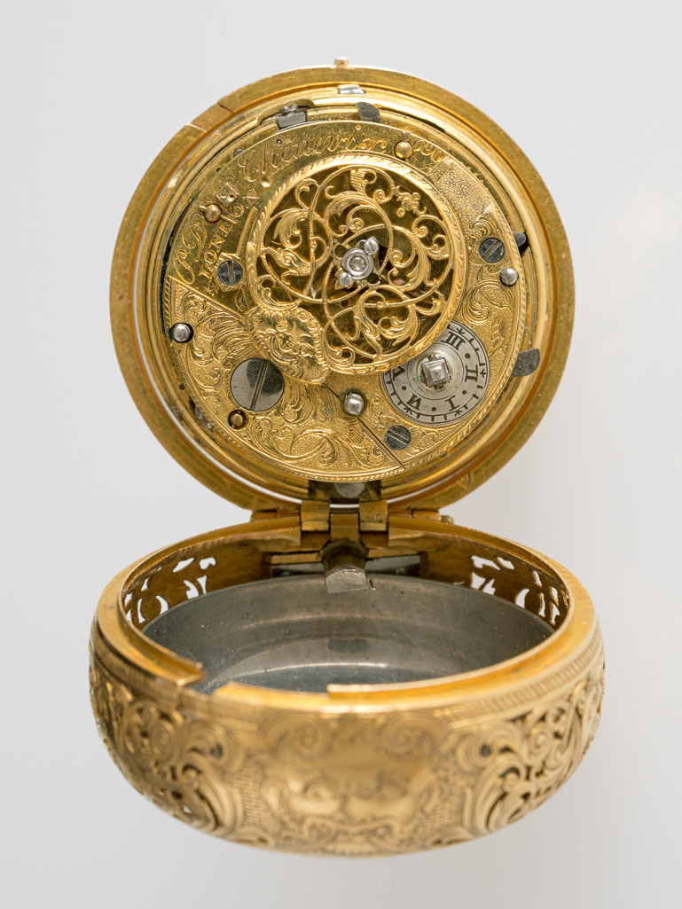 An image of Verge repeating watch in gold pair case. Chevenix, P. D., maker, England, London. Elin, Paul, case maker, possibly. MOVEMENT: Full plate movement engraved 'P D Chevenix 690', same on cap. Balance cock with pierced and engraved table, polished steel end piece with diamond end stone, mask at neck, foot chased. Brass balance. Slide plate engraved, silver regulation dial with radial Roman figures I to VI. Pierced fusee iron post. Case bolt in brass edge with nib through dial. Potance with short foot, riveted to plate. Counter potance, with square foot, riveted to plate. Plain repeating barrel, screwed to plate, outside flattened at edge of plate. Pillar plate with four turned pillars, third pinion sink. Fusee and chain, tangent set-up under barrel, barrel with top lip. Contrate wheel between hour rack and repeating barrel. Verge escapement. Train planted anti-clockwise. Five pinion runners governed by depthing pinion, second wheel in sink. Runners planted anti-clockwise. REPEATING WORK: 1/4 with chain repeating rack. All or nothing lever moved by hour can follower. Mechanism semi-polished. 1/2. 1/4 snail (a replacement), loose on cannon pinion, driven by spring into pinion. BRASS EDGE: Plain with joint. DIAL: White enamel on copper, ladder minute ring with diamond shaped quarter marks, and short radial Roman chapters. Counter enamel with painted 'W'. The dial is a replacement. HANDS: Gold, polished spade and poker. BELL: Scratched on the outside 'Drury' and '1.06.5'. CAP: Silver, oval table engraved as above, regulation crescent, winding pipe. Broad flat blued steel catch. Inside scratched '690' on table. INNER CASE: Gold, pierced and engraved band, with scene at pendant, mask at 6 o'clock. The back with a group of flowers, engraved at centre. Pendant, fixed by three screws, stirrup bow. Inside 'HM London 1742'. Maker's mark script 'PE' letter in rectangle with sharp corners. Body with cut-out for pulse piece. Plain bezel. OUTER CASE (A): Gold repousse with pierced pan