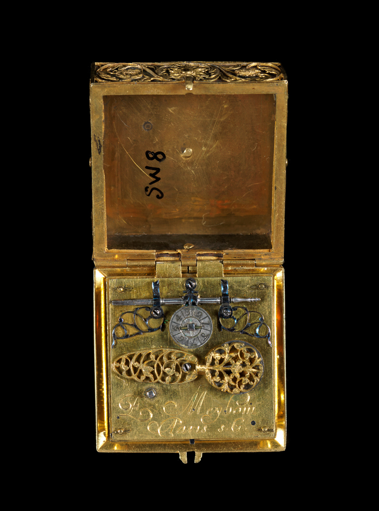 An image of Verge Watch. E. Meybom of Paris, St Germain. Square gold filigree case. Movement: Full plate square movement engraved ‘E. Meybom A Paris’. Balance cock with pierced table and large oval pierced foot, both with wavy edges. Steel balance. Tangent set-up above plate with dial, radial Arabic figures 1 to 8, above brass wheel, blued steel guard and pointer over endless screw, pierced blued steel brackets for endless screw. Square top plate. Shaped fusee iron post, straight blued steel fusee iron spring fixed with pin to plate. Blued steel case bolt pinned to plate. Rectangular potance with side engraved. Counter-potance screwed to under-side of plate. Square pillar plate with a baluster shaped turned pillar at each corner, border engraved around edge, hole for potance, 33' scratched on plate under dial. Fusee and chain, barrel with one lip (end turned after gilding). Train, of four pinions, set along bottom of plate, left to right. Verge escapement. Dial: Enamel on gold, three feet. Gold border, white enamel with painted blue, pink, red-brown and black corners. Black circle around radial Roman chapters, inner circle with quarter hour lines half hour lines extended between chapters. Gold circle, dial centre of translucent blue enamel over chasing. Hand: Plain steel formed hand with long beaded tail. Case: Square gold with sides and back of filigree work over blued steel panels. Gold bezel, engraved with leaf pattern, split at joint and with v for rock crystal/glass cover (crystal missing). Case Movement, height 41 1/4 mm, top plate A/F 18 2 mm, a/f 34 1/4 mm, pillar plate A/F 29.2 mm, thickness 14.2 mm, dial A/F 26.2 mm, pillar height 5.2 mm. Circa 1650. French.