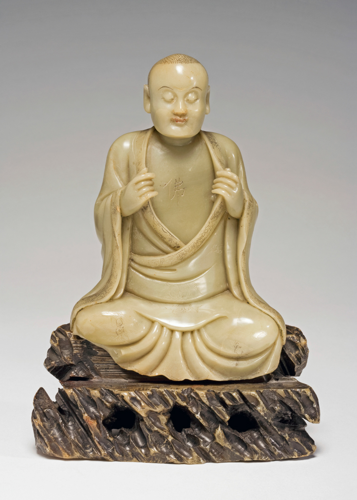 An image of Carving. Soapstone, carved as a seated luohan, the chest incised with a Fo (Buddha) character. The collar, sleeves and hem of his robes incised with a design of scrolling lotus on a formalized wave ground. Soapstone, height, including base, 17.8 cm, 1700-1800, Chinese.