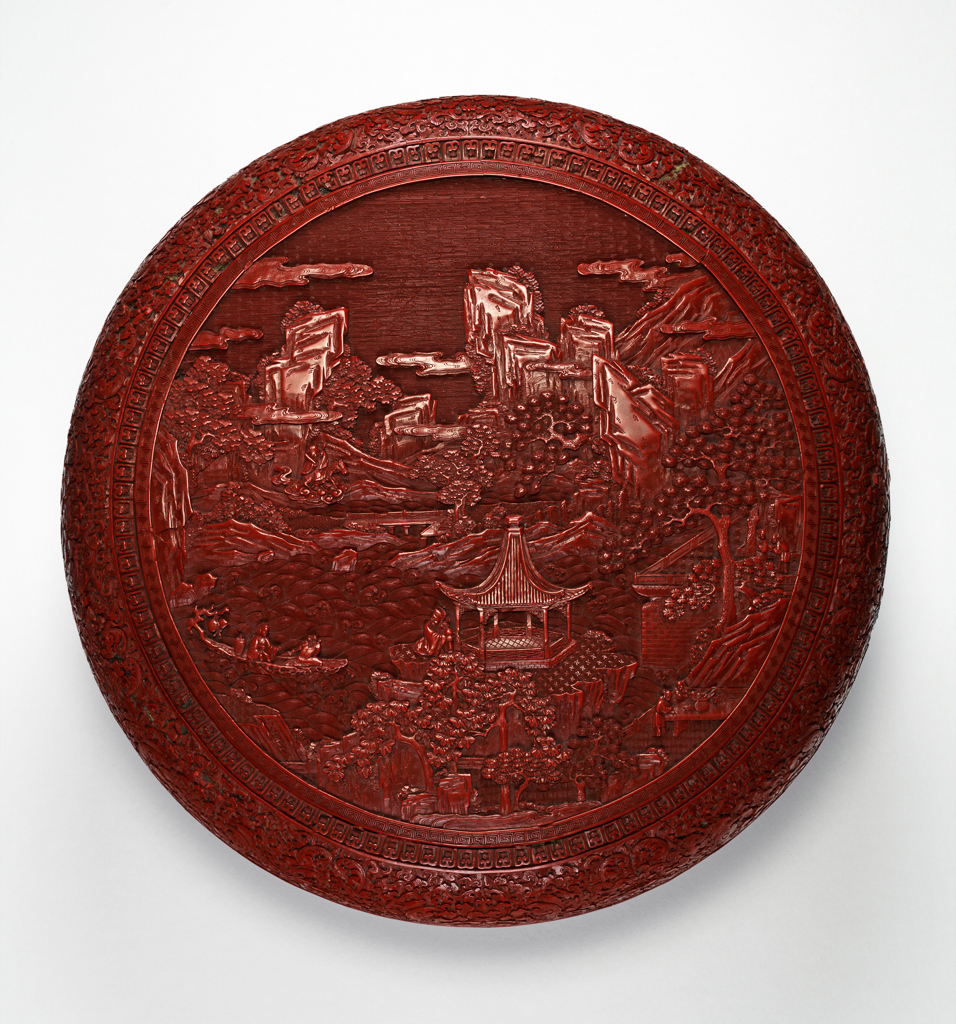 An image of Circular red lacquer box. The top is carved with a representation of 'The Happy Isles of the Blessed'. Carved and lacquered, diameter 47 cm, 1760-1820. Jiaqing period (1796-1820). Chinese.
