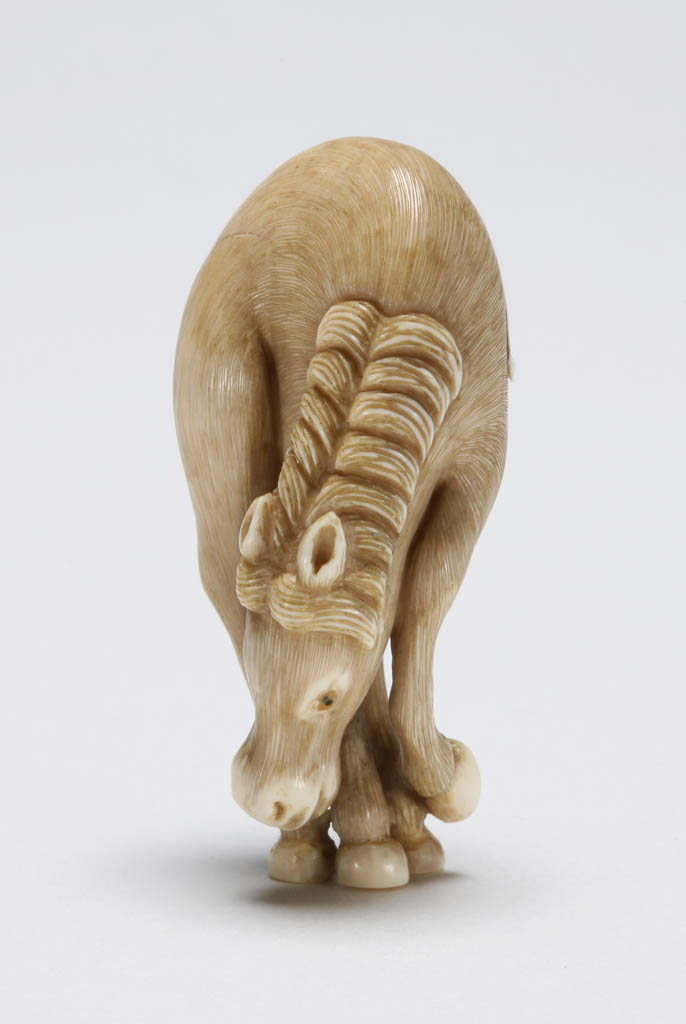 An image of Netsuke. Horse with its head bent down. The eyes are double inlaid with glass / resin. Unknown carver, Japan. Ivory, carved, circa 1980.