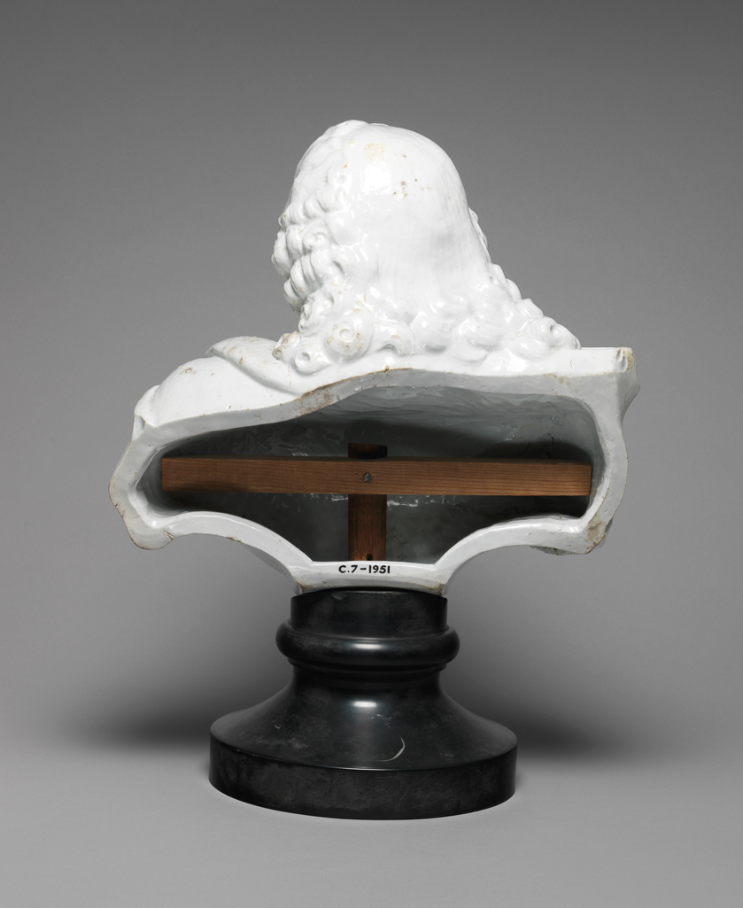 An image of Richard Chaffers' Factory (perhaps). Bust of George II (ruled 1727-60).  Bewigged, and wearing armour, the Garter Star, and a cloak draped about his shoulders and fastened with an oval cabochon brooch, supported on an associated black marble socle. Soft-paste porcelain (probably steatitic), press-moulded and glazed, height 44.5 cm (including socle), height 34.8 cm, width 30.5 cm, circa 1750-1760. England, Liverpool. Rococo.