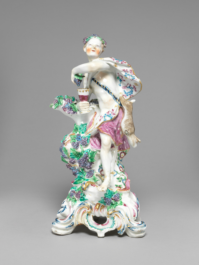 An image of Figure. Bacchus representing Autumn from a Set of Seasons. Bow Porcelain Manufactory. Soft-paste porcelain containing bone ash, press-moulded, with hand-modelled details, and very slightly blue-tinted lead glaze, painted underglaze in blue, and overglaze in enamels, and gilt. Height, whole, 26.7 cm, width, whole, 13.0 cm, circa 1765-1774. England, Essex, Stratford-le-Bow. Rococo.