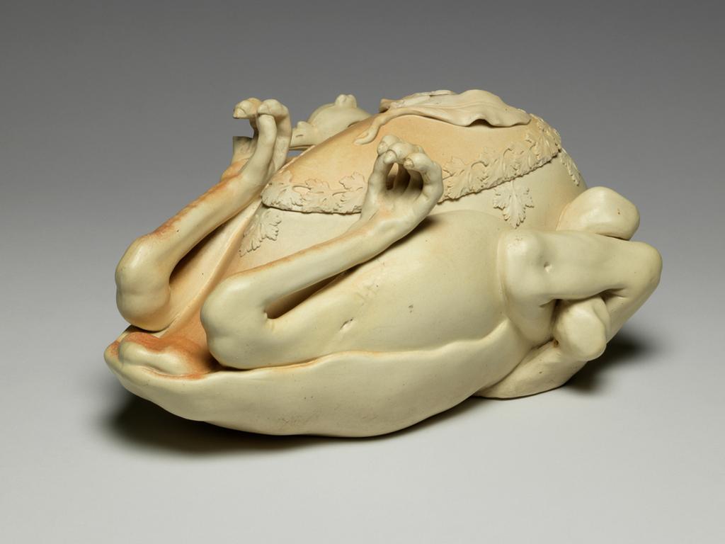 An image of Tureen and cover. ‘Pastry turkey’ tureen. John and William Turner, pottery, Staffordshire, Longton, Lane End. Moulded in the shape of a trussed and roasted fowl or game bird, breast upwards, with upturned feet and head tucked under one wing and egg-shaped cover fitting into breast. There is a relief moulded parsley garnish around the junction of the cover and body, and three moulded bay leaves which form a handle for the cover. Faint reddish-brown staining suggests roasting on parts of the upper surface. The interior is glazed. The underside is very slightly concave, with a narrow foot-rim. Cream stoneware, moulded, modelled and decorated with applied reliefs, height, whole, 15.5 cm, approx, length, whole, 33.6 cm, width, whole, 20.0 cm, approx, circa 1800. Production Note: Not dated, but social circumstances at this time indicate c.1800 the most likely date. Other examples dated c.1780-c.1820.