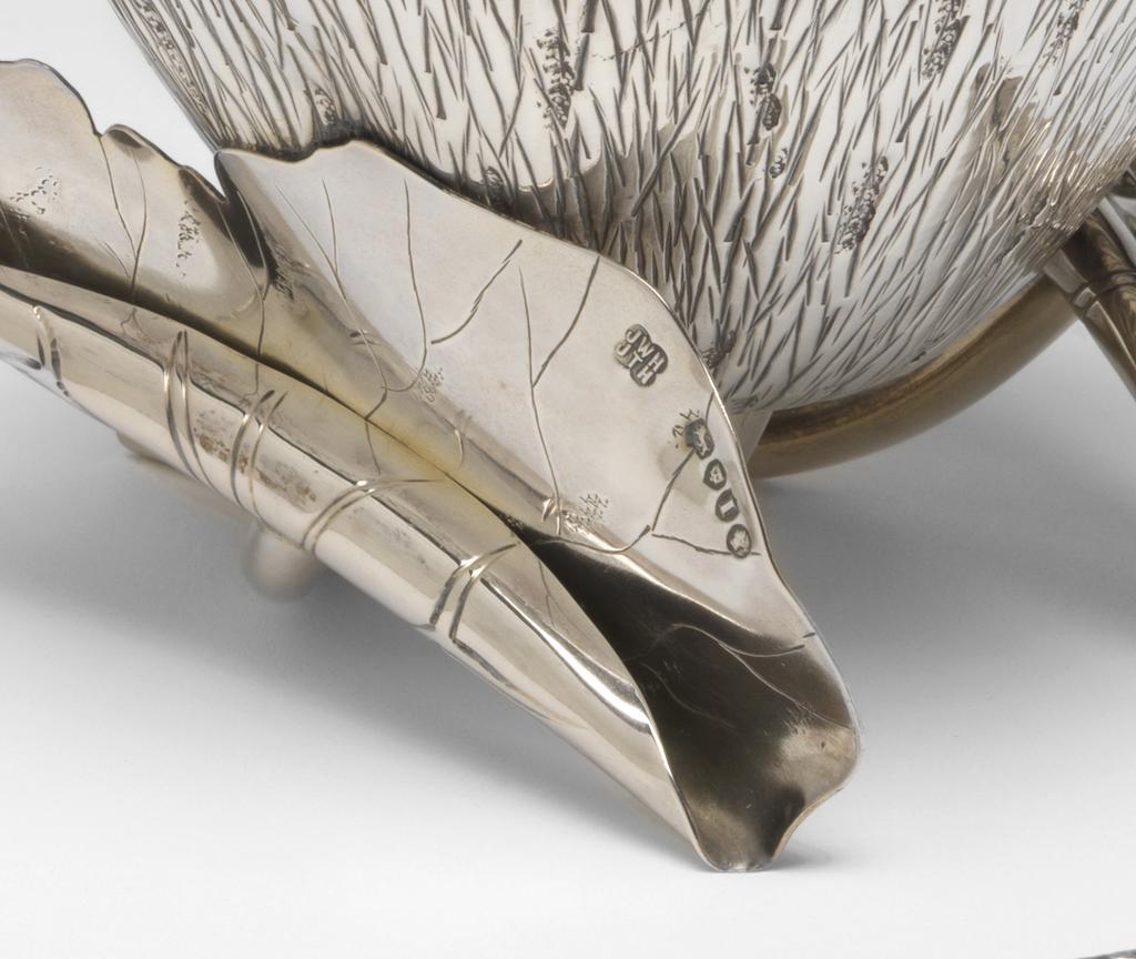 An image of Sugar bowl. Sugar sifter/spoon. Hukin, Jonathan Wilson, silversmith (British). Heath, Thomas, silversmith (British). Dresser, Christopher, designer, perhaps (British, 1834-1904). The bowl is in the form of a lotus flower with a lightly gilt interior, supported by a bent tubular stem, and two curled leaves with engraved veins and tubular stems branching out to right and left from beside the main stem. One leaf is completely curled, the other half open. The sifter spoon has a twig-shaped handle with forked terminal. It's bowl is of the same lotus flower form as the sugar bowl and it also lightly gilt; it is pierced with a pattern of lozenges and roundels. Silver, parcel-gilt, chased and engraved, height, bowl, 8.1 cm, varies, width, bowl, 12.4 cm, weight, bowl, 220 g, length, spoon, 14.9 cm, weight, spoon, 27 g, 1884-1885. Arts and Crafts. Production Note: The attribution of the design to Christopher Dresser is uncertain.