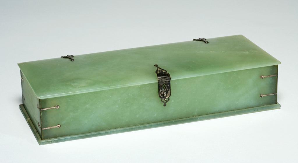 An image of Box. Pale green jade box, oblong shaped. The panels are flat without decoration.  The hinges are small and made of silver, as is the clasp and cornerstraps. Jade, silver, length 22.9 cm, height 5.1 cm, width 9.5 cm. Indian.