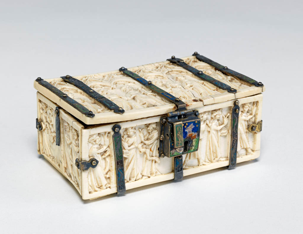 An image of Sculpture. Casket. Lid: Under six cusped arches with crocketted gables stand the figures of St Agnes, St Paul, St Peter, St John the Baptist, St Stephen, and St Catherine. Sides: Carved with scenes from the Martyrdom of St Catherine: her examination before Maxentius, the burning of the philosophers, the torture of the wheel, the beheading of the saint and her soul carried up to heaven. Mounts: Decorated alternately with panels of red, green and blue with pelican-like birds, salamanders and other fabulous beasts reserved in the metal. Lock-plate: Decorated with a hare in a field against a dark blue sky. Ivory, carved in relief,  with contemporary champlevé enamelled silver mounts. Height 4.4 cm, width 9.6 cm, depth 6.4 cm, circa 1370-1400. Production Place: Paris, France. Gothic. Medieval.
