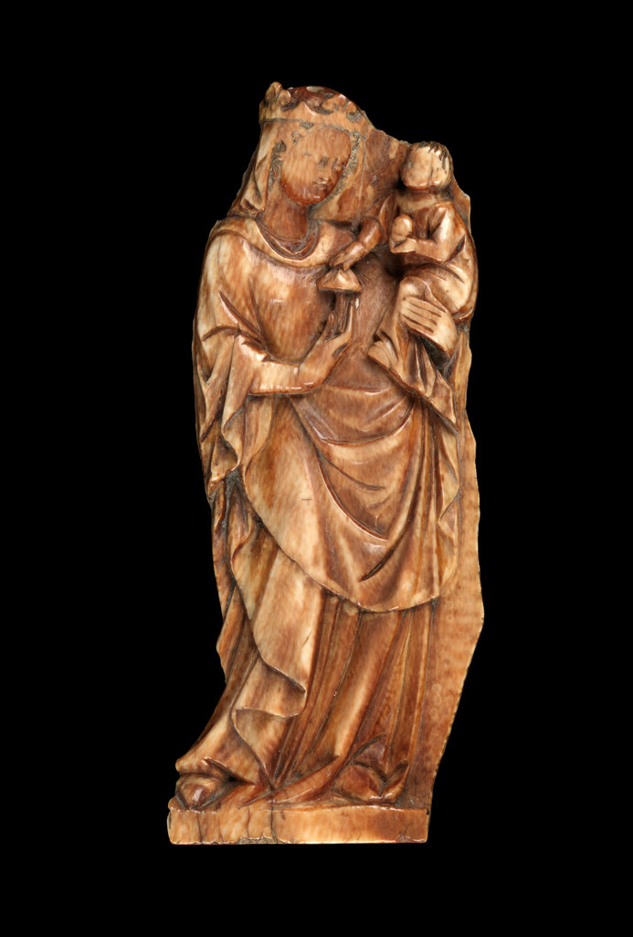 An image of Sculpture / Relief. Virgin and Child, carved in relief. The Virgin stands in an exaggerated swaying stance, holding the Child in her left arm. The Child holds a fruit in the left hand and with the right takes a flower (?) from the Virgin's right hand. The Virgin is crowned and wears a veil. Ivory, carved in relief, height, whole, 10.0 cm, width, whole, 3.7 cm, circa 1300-1400. Gothic. Medieval. French.