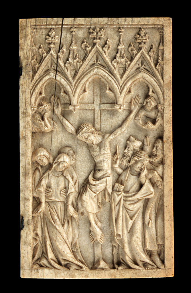 An image of Crucifixion. Right wing of a diptych. Under a triple arch with crocketted gables and pinnacles, Christ hangs on the cross in the centre. On the left the Virgin swoons into the arms of two holy women. On the right stands St John holding a book, and behind him two Jews. Above their heads on either side are two angels expressing grief. Ivory, carved, height, whole, 4 3/4 in, width, whole, 2 3/4 in, circa 1300-1400. Gothic, Medieval. French.
