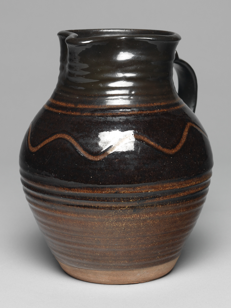 An image of Studio Ceramics. Slipware jug, light and dark brown with combed decoration. Cardew, Michael (British, 1901-1983). Earthenware, glazed, slip-coated, possibly made in the 1930s. Acquisition: Dr John Shakeshaft Bequest.