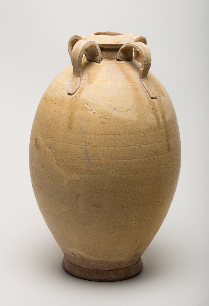 An image of Studio Ceramics. Tang style ovoid footed stoneware bottle, with an ochre glaze and four strap handles. Lo-Yang (maker). No mark. Height 14.5 cm, diameter, base, 6.9  cm, diameter, widest point, 17 cm, 700-799. Tang Dynasty (618-907). Chinese. Acquisition: Dr John Shakeshaft Bequest.