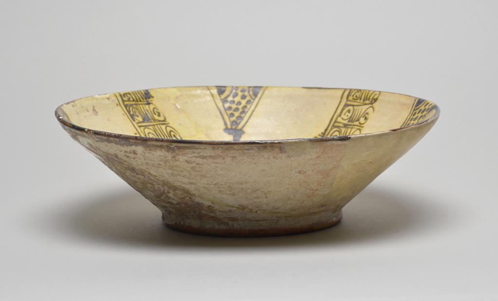 An image of Studio Ceramics. Earthenware bowl, much restored. White slip over buff body, with abstract decoration in black. Covered with a clear glaze. Production Place: Nishapur, Iran. 900-999. Samanid. Acquisition: Dr John Shakeshaft Bequest.
