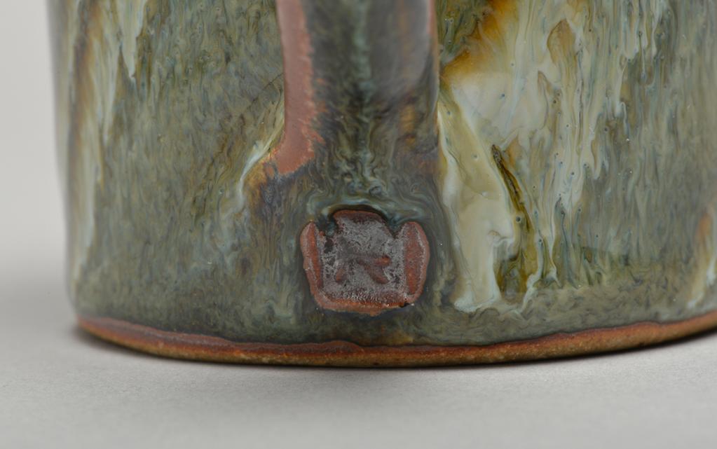 An image of Studio Ceramics. Cup and saucer. Hughes, Edward (British, 1953-2006). Olive ash glaze over red iron slip. The cup is decorated with diagonal trails. Height 9 cm, diameter, at extremeties, 14.8 cm, diameter, at base, 7.5 cm, before 2002. Acquisition Credit: Bequeathed by John Shakeshaft.