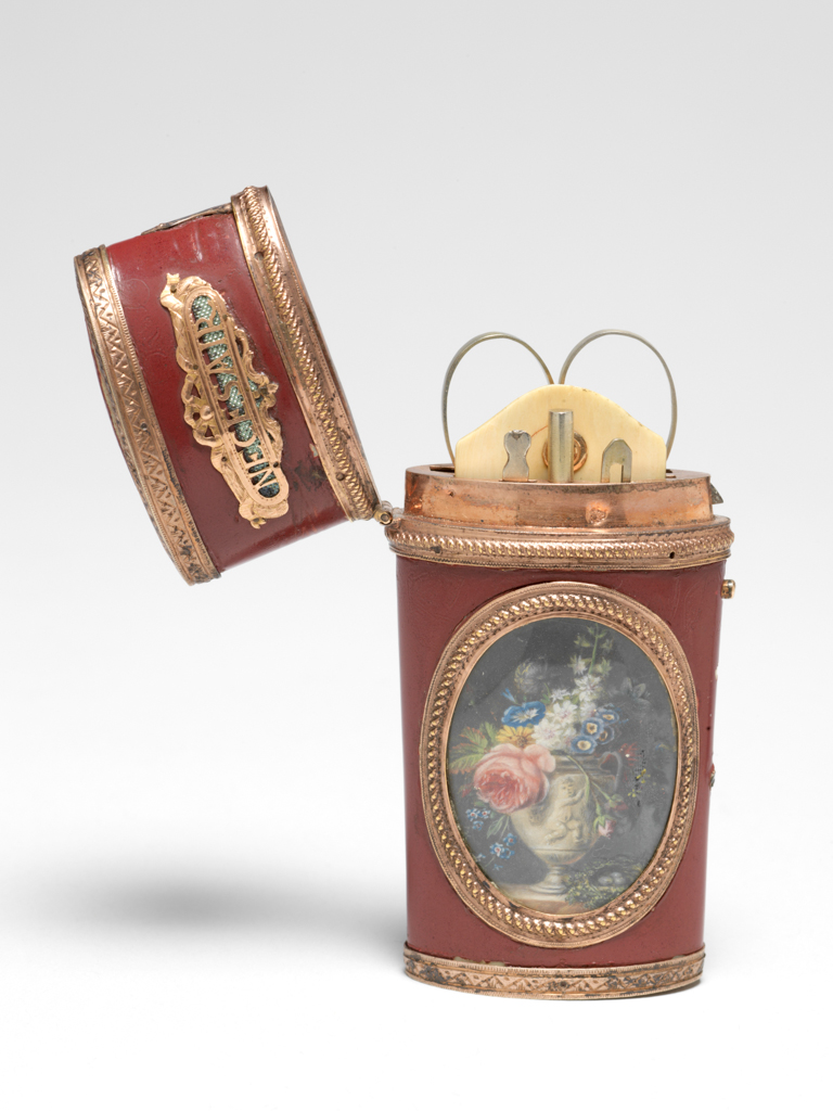 An image of Etui. Objet de vertu/nécessaire. Spaendonck, Gerard van (Dutch, 1746-1822). Unknown box maker, France. With an oval miniature of a carved stone urn of flowers and a nest. The tapering flattened cylindrical etui necessaire has a slightly domed hinged lid with a catch, which is released by a button on the right hand side with a thumb plate above. The mounts round the miniature, initial and rims are embossed with ropework, those at the top and bottom of the etui are engraved with a pattern of zig-zags and scrolls. The front and back of the lid each have an openwork gold plaque pinned over pale green metallic foil, bearing the words 'NECESAIR' and 'D’AMITIE' respectively, framed by ribbons. On the front is a miniature, possibly painted on card. On the back is an elaborate gold openwork initial 'A' on a green metallic foil ground, under glass. The miniature depicts a two-handled stone vase carved with a cherub, containing flowers including roses, hyacinth, forget-me-nots, auricula and morning glory, next to a nest of leaves containing three eggs, all on a marble slab against a dark grey ground. The etui contains a pair of scissors, an ivory tablet with a gold stud, a pencil, a bodkin and another implement in separate compartments lined with red velvet. Red lacquer, probably on ivory, with gold mounts, a miniature on the front face and an initial on the back. Height, whole, 2.1 cm, length, whole, 8.0 cm, width, whole, 5.0 cm, circa 1766 to before 1822. Collection: Major, the Hon. H.R. Broughton.