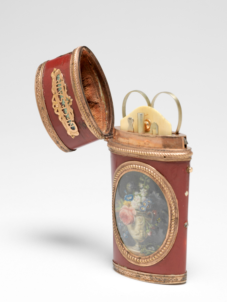 An image of Etui. Objet de vertu/nécessaire. Spaendonck, Gerard van (Dutch, 1746-1822). Unknown box maker, France. With an oval miniature of a carved stone urn of flowers and a nest. The tapering flattened cylindrical etui necessaire has a slightly domed hinged lid with a catch, which is released by a button on the right hand side with a thumb plate above. The mounts round the miniature, initial and rims are embossed with ropework, those at the top and bottom of the etui are engraved with a pattern of zig-zags and scrolls. The front and back of the lid each have an openwork gold plaque pinned over pale green metallic foil, bearing the words 'NECESAIR' and 'D’AMITIE' respectively, framed by ribbons. On the front is a miniature, possibly painted on card. On the back is an elaborate gold openwork initial 'A' on a green metallic foil ground, under glass. The miniature depicts a two-handled stone vase carved with a cherub, containing flowers including roses, hyacinth, forget-me-nots, auricula and morning glory, next to a nest of leaves containing three eggs, all on a marble slab against a dark grey ground. The etui contains a pair of scissors, an ivory tablet with a gold stud, a pencil, a bodkin and another implement in separate compartments lined with red velvet. Red lacquer, probably on ivory, with gold mounts, a miniature on the front face and an initial on the back. Height, whole, 2.1 cm, length, whole, 8.0 cm, width, whole, 5.0 cm, circa 1766 to before 1822. Collection: Major, the Hon. H.R. Broughton.