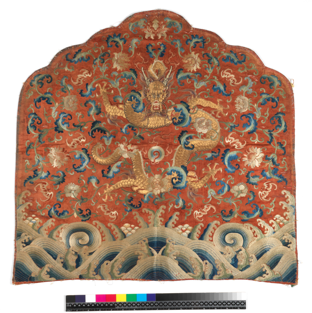 An image of Textiles. Throne back cushion cover. Unknown maker, China. Five-clawed dragon above waves, background pattern of peonies and bats. Satin; red ground. Metallic thread and silk embroidery - blues, greens, beiges, red, pink and grey; satin and stem stitch, couching. Height, whole, 60 cm, width, whole, 63 cm, circa 1775-circa 1780. Acquisition Credit: Given by Mrs. Soame Jenyns, in accordance with the wishes of her late husband, Soame Jenyns.
