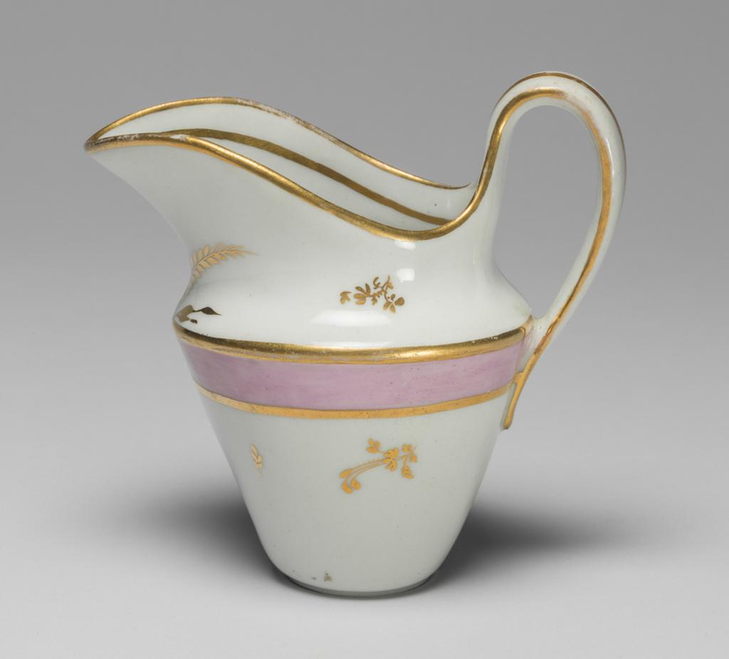 An image of Milk jug. New Hall Porcelain Factory, Staffordshire. Hybrid hard-paste porcelain milk jug from a teaset, decorated overglaze with pink enamel and gilt. Decorated with a wide band of pink enamel between narrow gold bands and with scattered floral sprigs in gold, with two sprays of leaves below the lip. Pattern no. 223. Height 11.5 cm, 1785. See C.11A-L-1988: A service comprising a teapot and cover of 'silver' shape, a milk jug, sugar basin and cover, a slop basin, two plates of different sizes, two tea bowls, two coffee cups and two saucers.