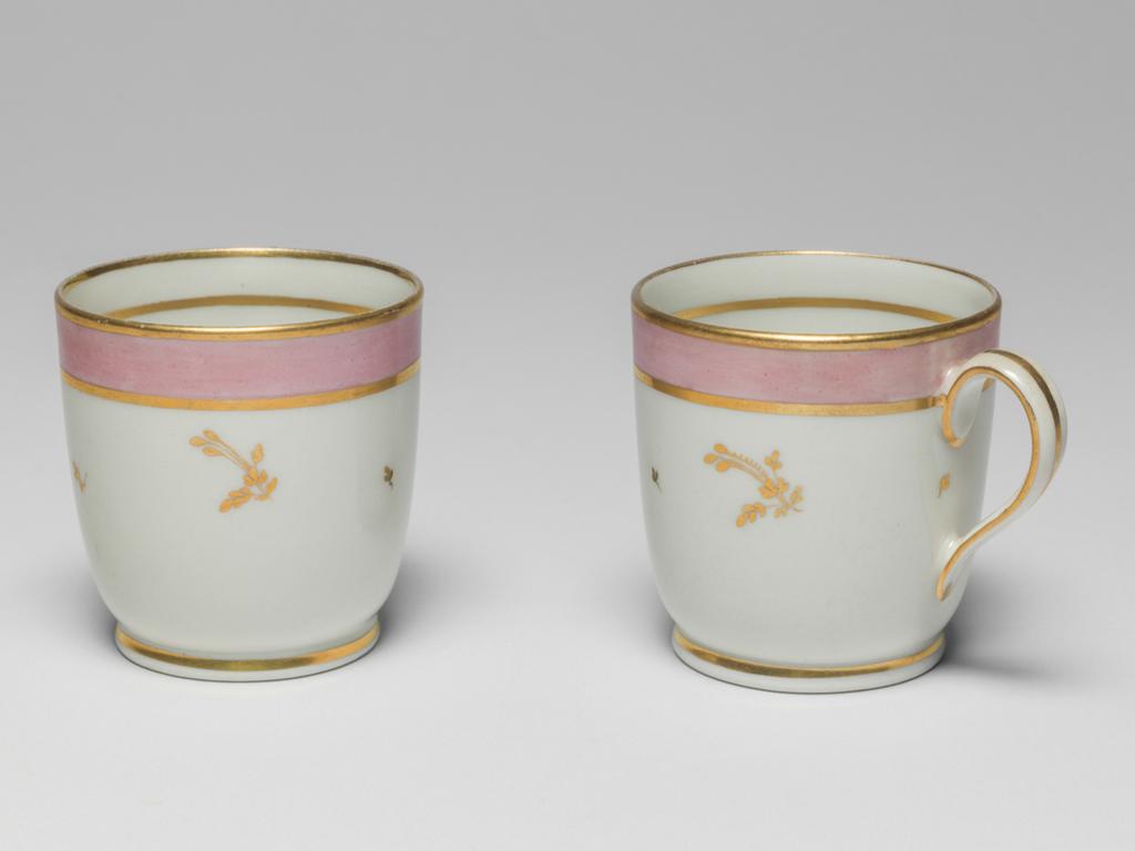 An image of Coffee cups. New Hall Porcelain Factory, Staffordshire. C.11G-1988 & C.11-H-1988: Hybrid hard-paste porcelain coffee cup, from a teaset. Decorated overglaze with a wide band of pink enamel between narrow gold bands and with scattered floral sprigs in gold. Pattern no. 223. Height 6.6 cm, 1785.See C.11A-L-1988: A service comprising a teapot and cover of 'silver' shape, a milk jug, sugar basin and cover, a slop basin, two plates of different sizes, two tea bowls, two coffee cups and two saucers.
