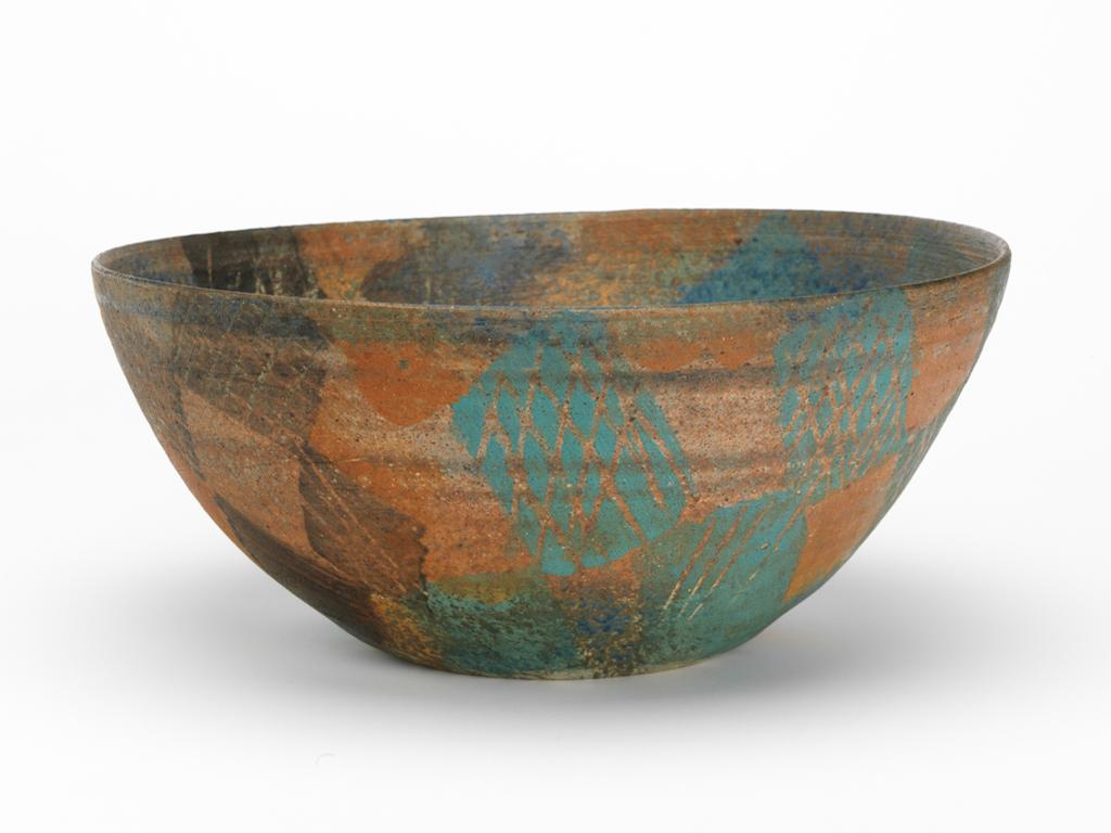 An image of Studio Ceramics. Wide Bowl. Abbaro, Mo (b. Sudan, 1935-2016). Large hemispherical bowl with base flattened on the outside. Decorated inside and out, mainly in earth colours: green, browns and blue. Irregular patches of coloured slip applied over each other; on exterior some applied through a mesh and small areas of unpainted clay near the base; on interior the surface scratched with sgraffito lines. Matt surface. Underside unpainted. Porcelain and ‘T material’, thrown, painted with coloured slips, and decorated with sgraffito. Height 17 cm, diameter 39 cm, 1985.