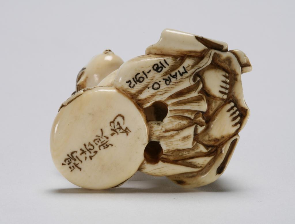 An image of Netsuke. Woman, naked to the waist washing her face, with a flat two-handled bowl. Hō Hōgen, Japan. Inscription: signature, with kakihan. Created by Hō Hōgen. Ivory, with carved and stained detail, width 4 cm. Japanese.
