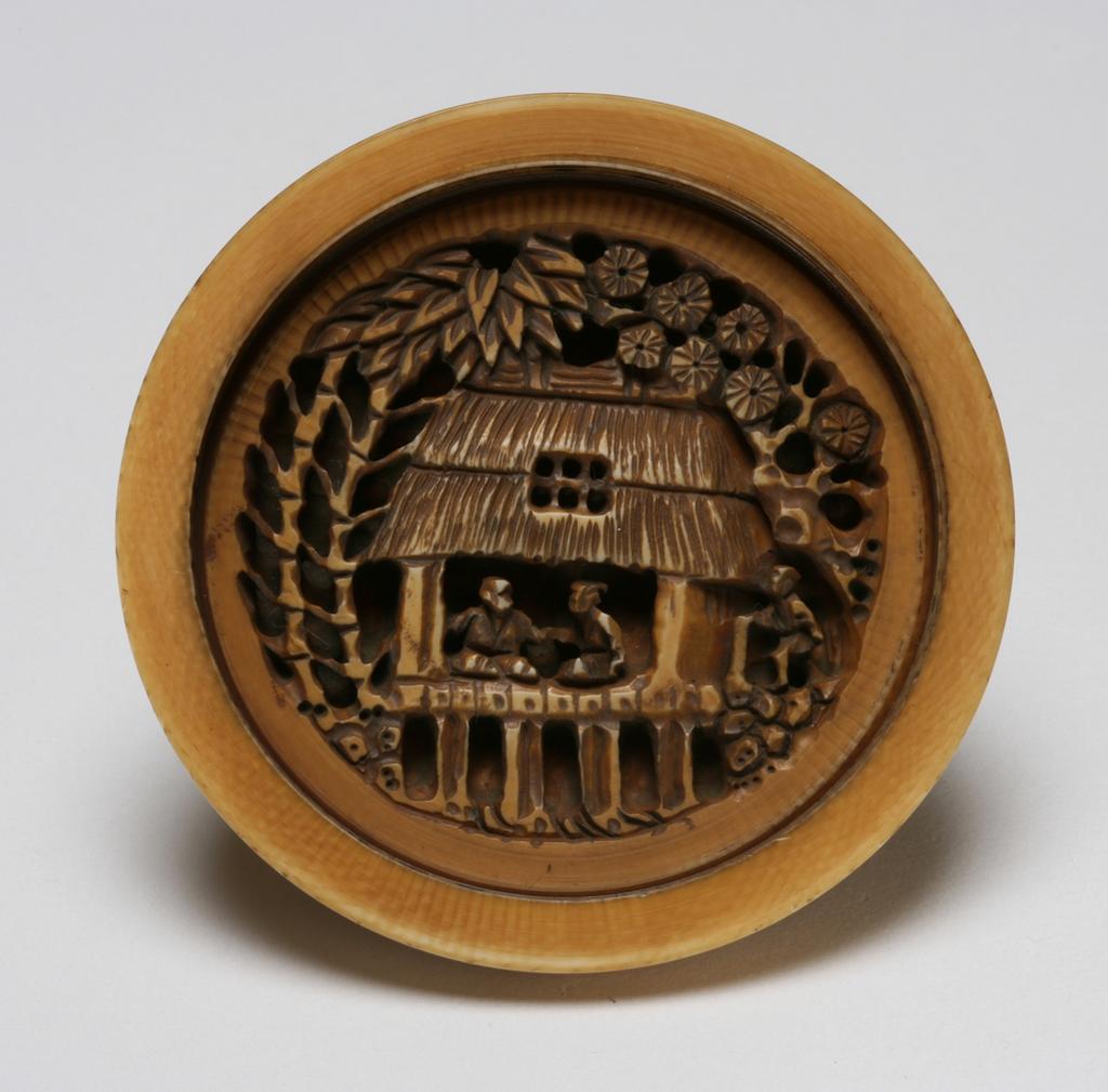 An image of Manju. Unknown maker, Japan. There are two halves of this Manju, one is the scene of farmers working with the water mill pumping river water for irrigation of the farm, the other half is the scene of two villagers in a house enjoying tea underneath bamboos and pine trees. These two halves can be screwed tight together. Ivory, carved, 1800-1899.