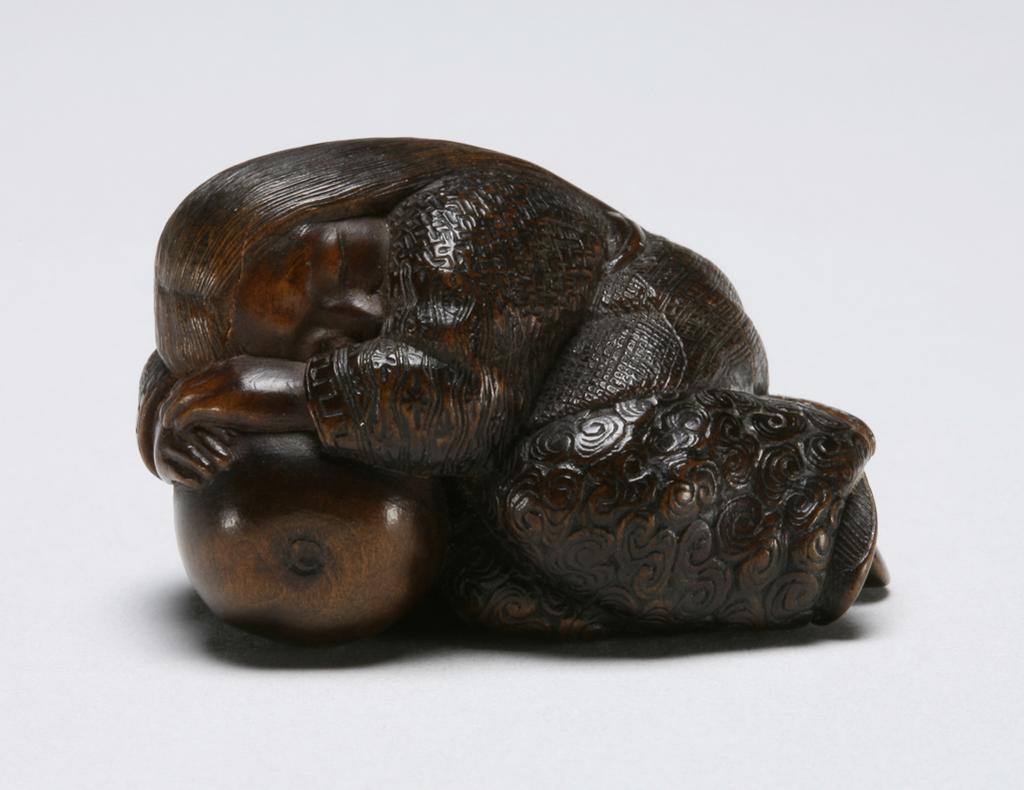 An image of Netsuke: katabori. Sleeping Shojo. Hokutei, Edo Period (1603-1868), Japan. Figure of Shojo curled up and sleeping, her head and hands resting on a double gourd flask, the stalk forming the himotoshi. Details of her hair and costume finely incised. Wood, finely carved, incised and stained, height, whole, 2.6 cm, width, whole, 3.9 cm, circa 1800-1868. Edo Period (1615-1868).