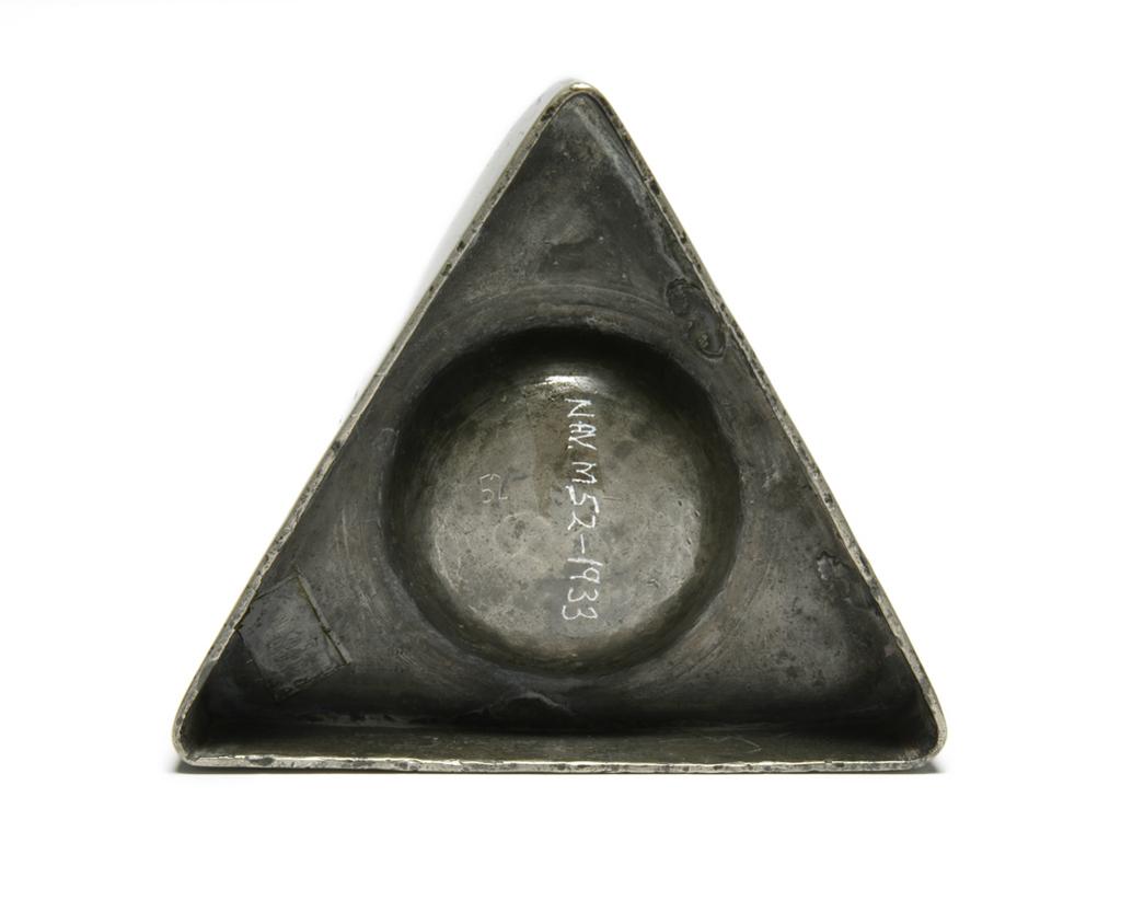 An image of Salt. Unknown production, England. Triangular pewter salt, with wrigglework. Incised with the initials 'EHC'.  Marked SO in a dotted circle, and struck twice. Pewter, incised, engraved, height, 2.5, cm, circa 1650. Declared fake by the Pewter Society, October 1953. Style of mid 17th century. Collection: Antonio de Navarro Collection.
