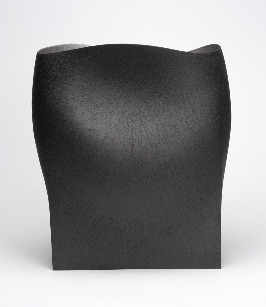 An image of Studio Ceramics. Undulating Vessel. Hanna, Ashraf (b. 1967, Egypt). Hand-built raku body clay coated with near-black slip. Hand built clay vessel, rising from a sharply pointed rectangular base. The sides flat at the base, rising into a softer curving form with a bulge on one side and a large dimple on the other, one slightly lower than the other giving a listing appearance. Undulating rim. Coated with near black slip and finely textured inside and out. Underside flat. Height 33 cm, width 30.5 cm, depth 20.5 cm, 2018. Gift of Nicholas and Judith Goodison through the Art Fund.