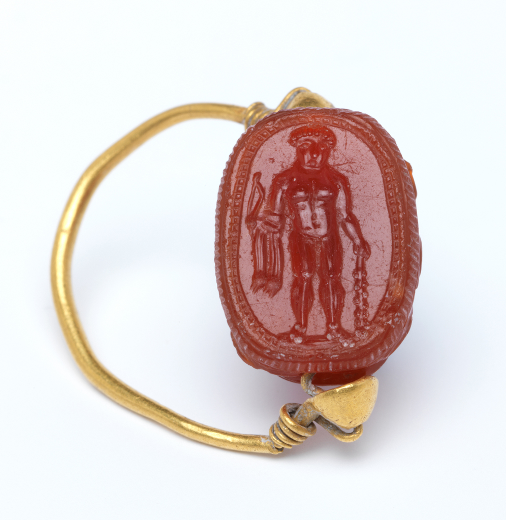 An image of Engraved gems/scarab/intaglio. Heracles, facing front, wearing lionskin and holding club and bow.  Intaglio cutting, carnelian, height 15 mm, width 11 mm, depth 8 mm, circa 400- circa 301 B.C. Etruscan.