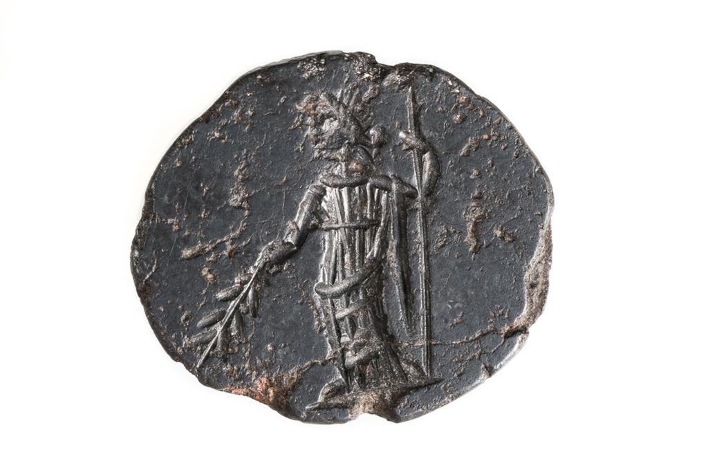 An image of Engraved gems. Magical amulet. Obverse: a standing female figure, dressed in a chiton and a himation which is draped around the lower half of her body and hangs over her left shoulder. The figure supports herself with a long staff or sceptre held in her left hand. She holds what appears to be a palm frond in her extended right hand. She wears a wreath, and her hair seems to be arranged in horizontal furrows across her head. Reverse: inscription in two lines 'NAC' the bevel is equally inscribed. Intaglio cutting, hematite, 21 mm x 18 mm, circa 200- circa 400 AD. Roman Imperial.