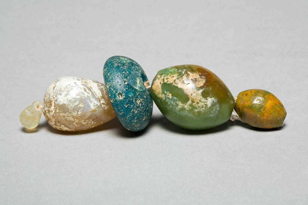 An image of Jewellery/Beads (4). Find Spot: tombs Aleppo, Israel. Light blue glass and chalcedony. Persian-Roman period.
