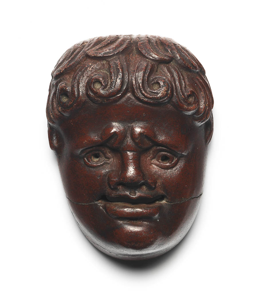 An image of Mask of a New Comedy Youth. Coffin attachment. Moulded, porphyry (imitation), length 6.7 cm, width 4.8 cm, circa 50-100 AD. Egyptian, Roman period.