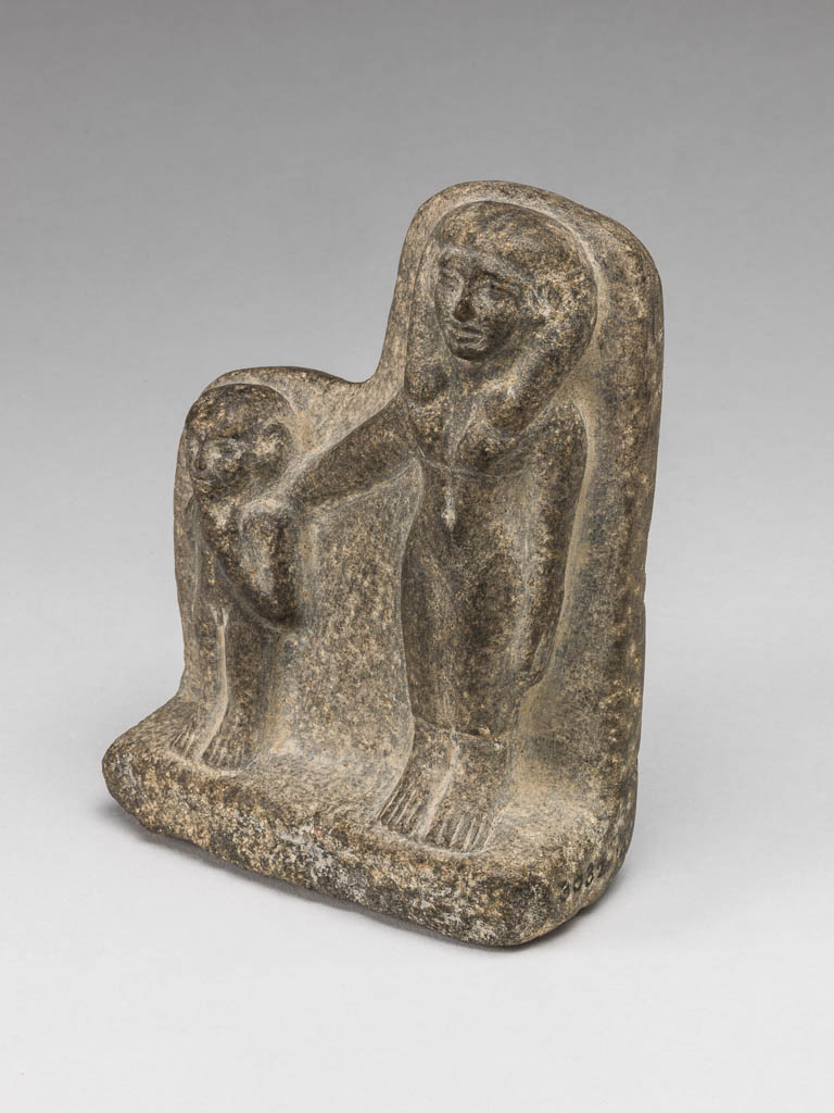 An image of Figure/Statuette of a female figure and a boy. The woman has her right arm stretched out around the boy's shoulders; the boy has his left forefinger on his lips. Diorite, carved, height 11.5cm, 2055-1650 B.C. Middle Kingdom; Twelfth Dynasty. Find Spot: Haraga, Egypt.