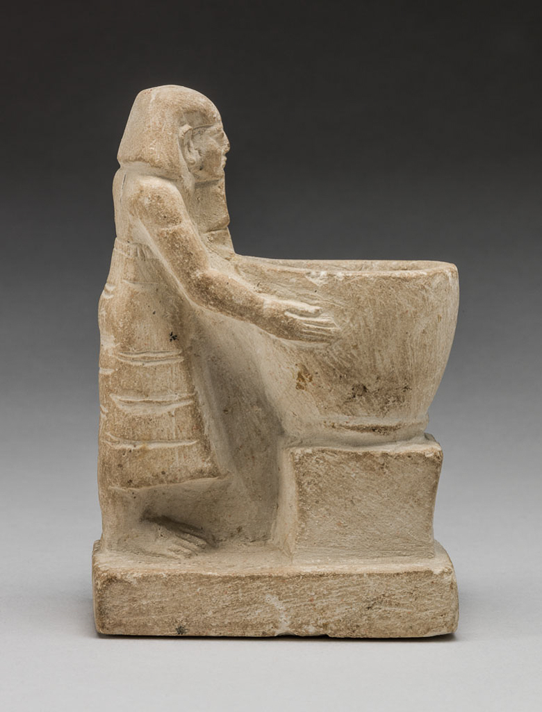 An image of Figure/Statuette. Priest, standing, holding a large bowl before him. Production Place: Egypt. Find Spot: Haragah, Egypt. Limestone, carved, length 8.6 cm, 2055 -1650 B.C. Twelfth Dynasty. Middle Kingdom.