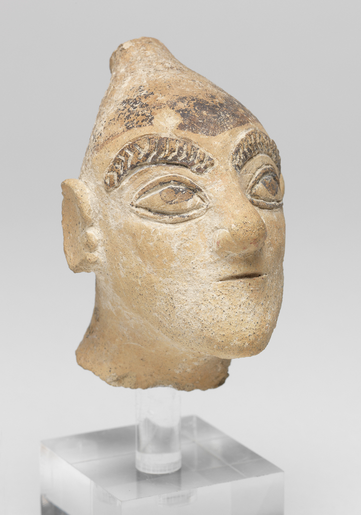 An image of Figure/Head. Head of charioteer. Production Place: Cyprus. Find Spot: Salamis, Cyprus. Clay, moulded, height 0.076 m, width 0.048 m, 600-501 B.C. Archaic Period.