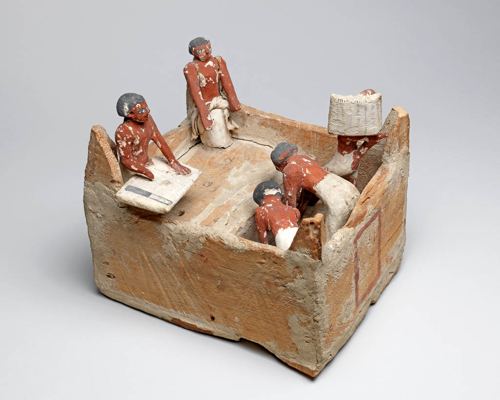 An image of Model of a granary: a square building with steps leading up to a platform. Two men prepare to lift a sack each: one man carries a sack up the steps; two men sit in the corners of the building - one is a scribe with writing board and palette on his knee. Plastered wood, painted yellow, red-brown (flesh), white and black. One man wears a cloth garment. Production Place: Egypt. Find Spot: Beni Hasan; tomb 366 (Khety). Wood, plaster, linen, painted, height 25 cm, length 29 cm, width 23.6 cm, circa 2010- circa 1950 B.C. Twelfth Dynasty; Middle Kingdom.