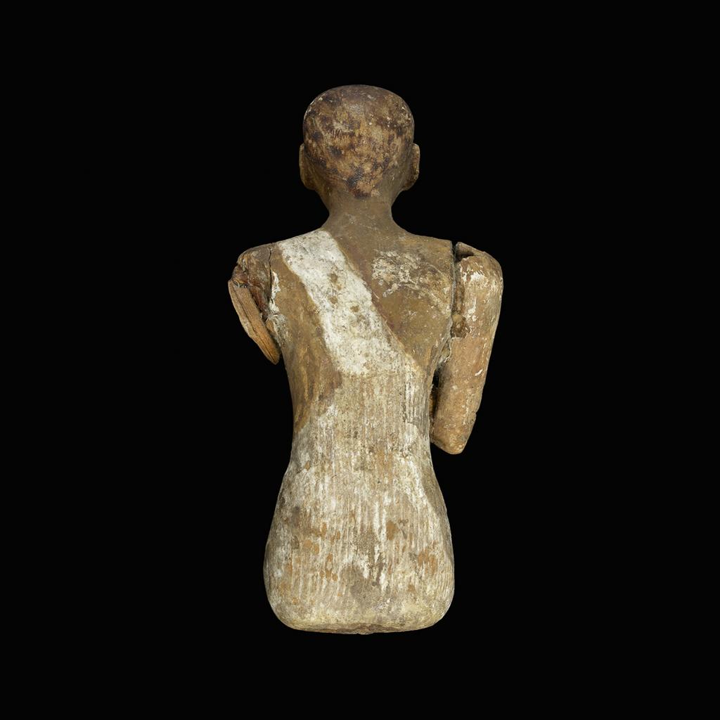 An image of Figure/statuette. man, seated, with right arm on his chest, left arm and legs are missing. Height 0.13 m. Middle Kingdom.