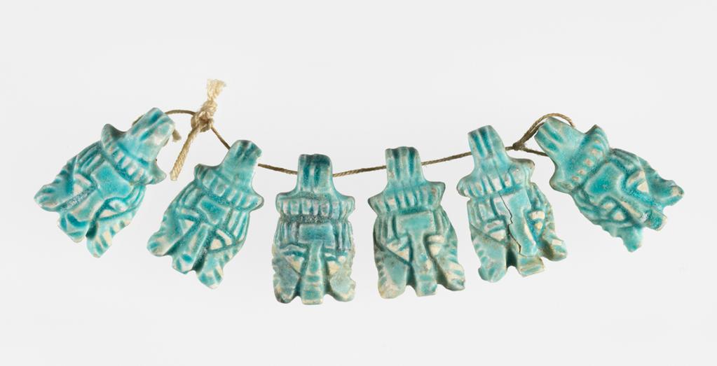 An image of Jewellery. Amulet. Glazed beads. 6 faience lion head pendants or amulets; green-blue in colour. Each is identical and made from the same mould. It is possible that they represent the god Bes, who takes features from a lion, but they are too stylised to say for certain. found in tomb 1010 in the Sanam cemtery. Production Place: Nubia. Find Spot: Meroe Sudan; grave 1010. Faïence, mouldmade, length 0.01 m, circa 700 B.C. to circa 600 B.C. Meroitic Period, Third Intermediate period.