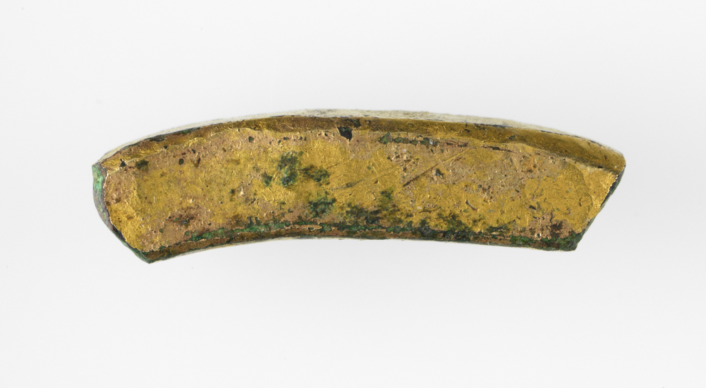 An image of Fragment. A curved section of gilt copper-alloy. It is square in cross-section and is broken at both ends. It has been worked as each of the four faces are flat and the vertices have been hammered into small flat surfaces as well. Find Spot: Torksey, Lincolnshire. 500-1500. Medieval.