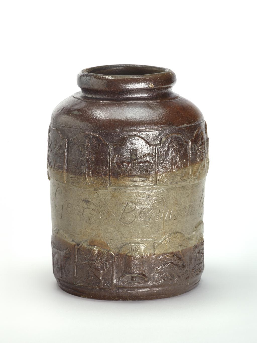 An image of Pickle jar. Unidentified pottery, possibly London. The jar is cylindrical with curved shoulders, a short incurved neck and rolled mouth. Round the middle are incised the names and date 'George Bennison & Sarah Nov 28 1752', Above and below this, there is a band of adjacent inn-signs. Above: The Four Swans, The Grenadier, The Crown, The King's Head (with initials GR), the Duke of Marlborough (DM), The Peal of Bells (eight bells and bell ringers), The Sun, The Jolly Sailor, The Star, The Hart, and The Noah's Ark. Below: The Bull, The Griffin, The Bell, The Swan, The Rose (with the name Wm Hasmere?), The Castle (? part missing), The Angel, The Spread Eagle, another missing, and The Angler (?). Greyish buff stoneware, thrown, decorated with applied moulded reliefs, coated with dark brown dip on the upper and lower part of the sides, and salt-glazed, height, whole, 27.3 cm, dated 1752.
