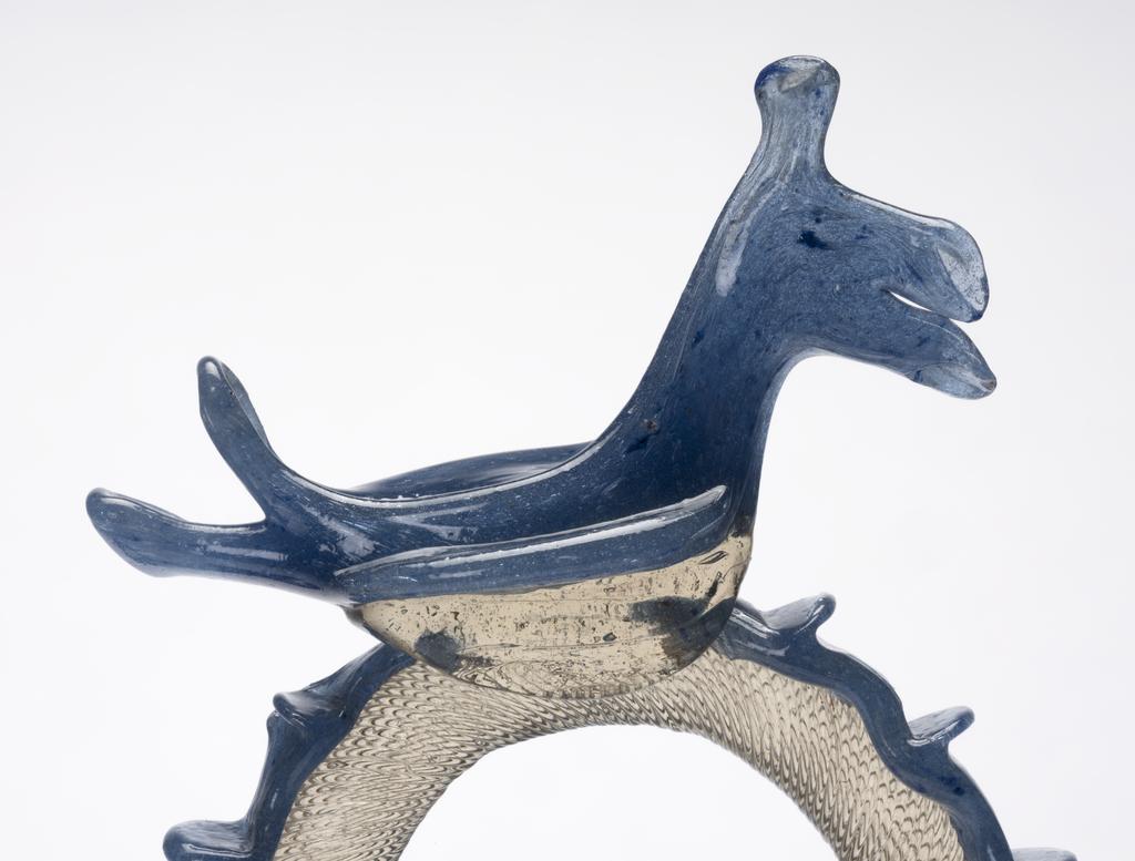 An image of Continental glass. Càntir. Pouring vessel for wine. Unknown glasshouse, Spain, Catalonia. Pale yellowish bubbly glass with opaque white threads, applied blue glass decoration and bird finial. Height, whole, 27.8 cm, width, whole, 17.3 cm, circa 1700-1750, possibly late 17th century. Production Note: A càntir is a vessel for pouring water. The word derives from the Spanish cántaro, a ceramic jug. This form is one of several typical of Catalonian glass production. Sir Ivor and Lady Batchelor Bequest through The Art Fund.