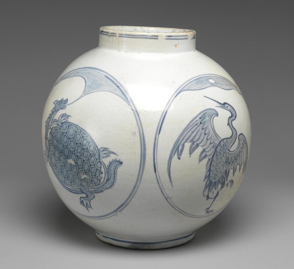 An image of Large jar with tortoise and crane designs. Unknown pottery, Korea, Kwangju, Punwon-ri kilns. The body of this jar is almost globular and the neck straight; the foot is wider than the neck, giving the jar a stable appearance. In four roundels around the sides, divine tortoises and cranes are arranged in alternation, with a cloud or auspicious vapour issuing from the mouth of each tortoise, and with lots of free space around the designs. The glaze is of milky-white colour and crackled, the body is thick and heavy. On the base is an unexplained straight incised line and traces of sandy supports adhere to the footring. Porcelain, thrown, painted in cobalt-blue, and glazed, height, whole, 31.0 cm, diameter, rim, 14.0 cm, diameter, foot, 15.0 cm, circa 1750-1800. Choson Dynasty (1392-1910). Notes: Such jars (hangari) were used as wine vessels.