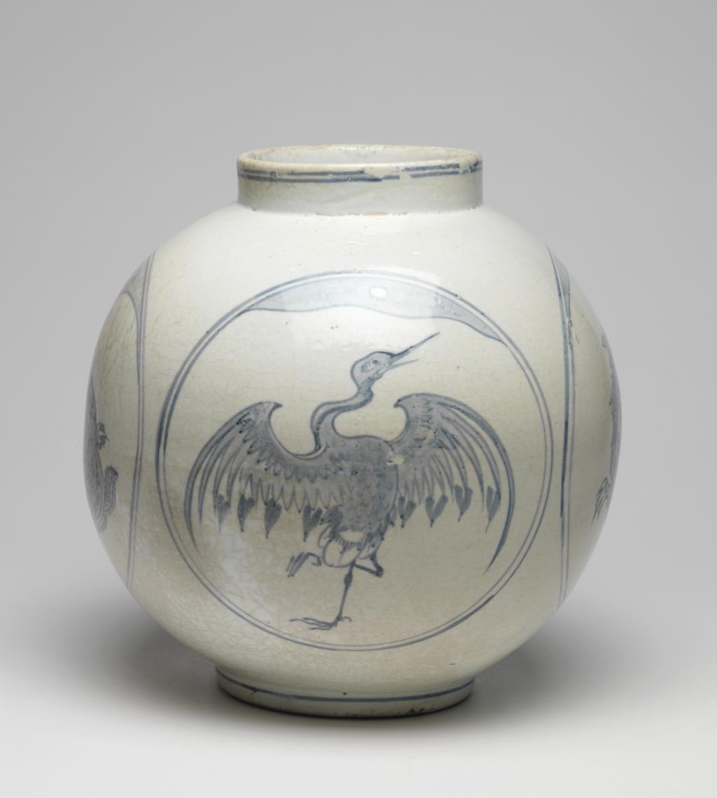 An image of Large jar with tortoise and crane designs. Unknown pottery, Korea, Kwangju, Punwon-ri kilns. The body of this jar is almost globular and the neck straight; the foot is wider than the neck, giving the jar a stable appearance. In four roundels around the sides, divine tortoises and cranes are arranged in alternation, with a cloud or auspicious vapour issuing from the mouth of each tortoise, and with lots of free space around the designs. The glaze is of milky-white colour and crackled, the body is thick and heavy. On the base is an unexplained straight incised line and traces of sandy supports adhere to the footring. Porcelain, thrown, painted in cobalt-blue, and glazed, height, whole, 31.0 cm, diameter, rim, 14.0 cm, diameter, foot, 15.0 cm, circa 1750-1800. Choson Dynasty (1392-1910). Notes: Such jars (hangari) were used as wine vessels.