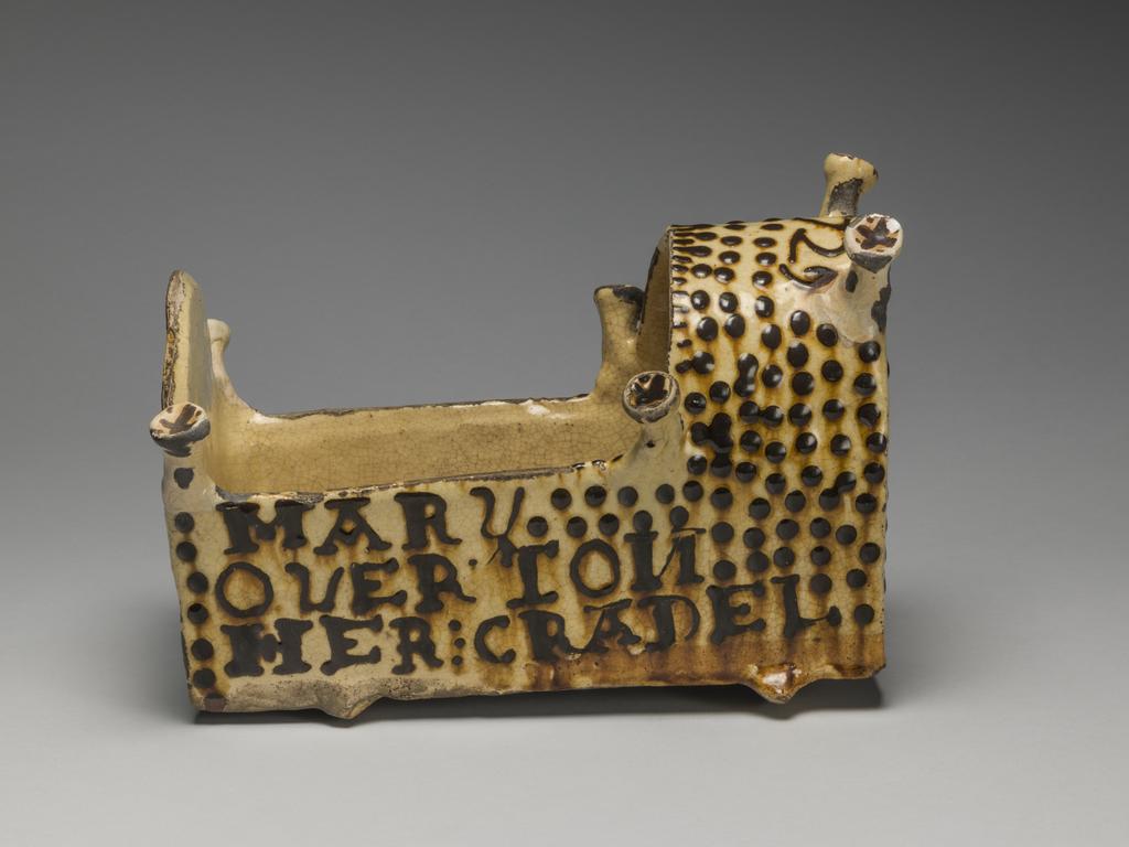 An image of Model Cradle/Commemorative Crib. Inscribed, 'MARY OVERTON – HER CRADEL, 1729'. Staffordshire pottery. Lead-glazed earthenware, slipware. English.
