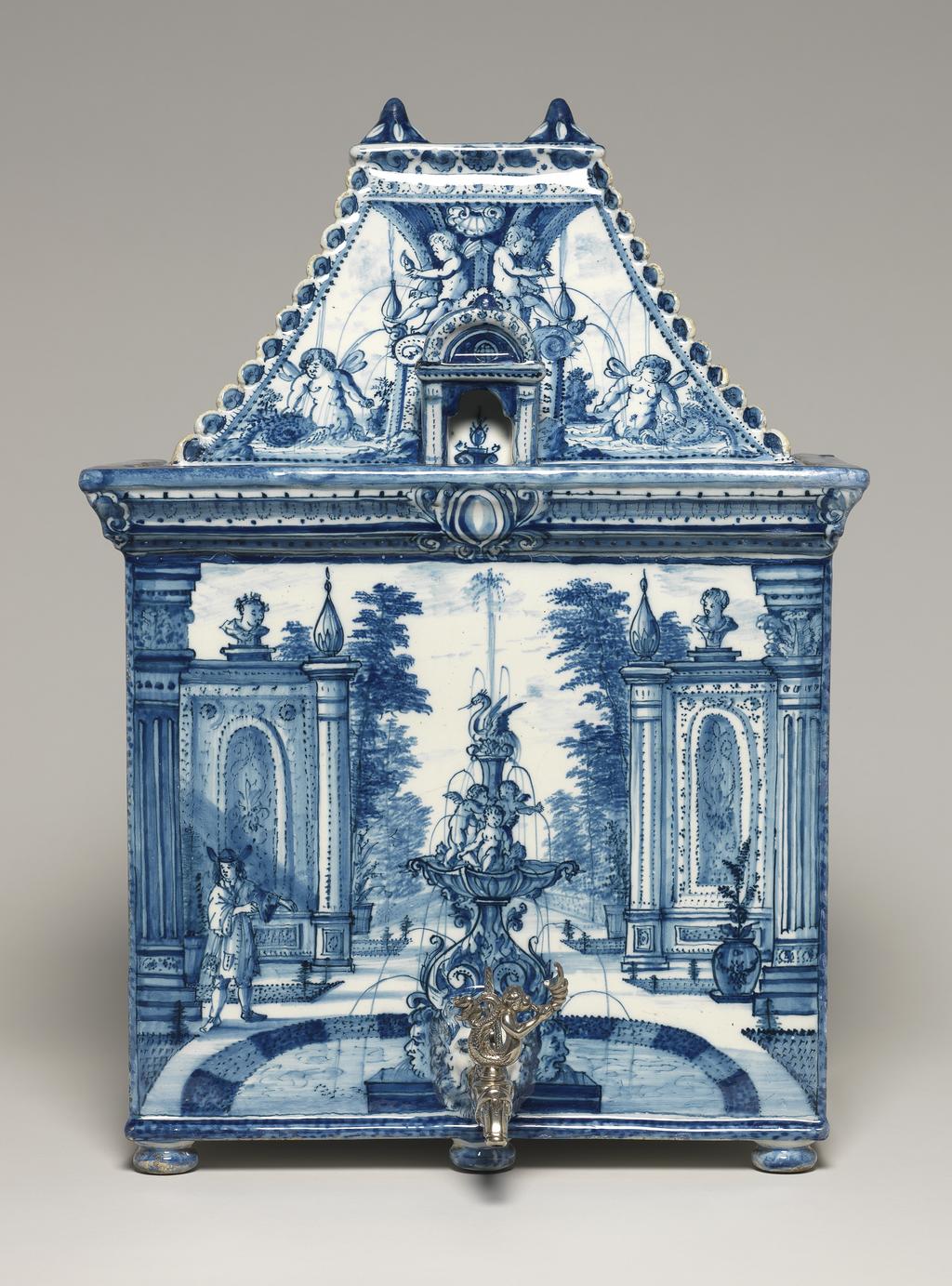 An image of House-shaped cistern with detachable roof, and applied silver spigot. Greek A Factory. Kocks, Adriaen (proprietor, Dutch potter, active 1686-1701). Tin-glazed earthenware, moulded in two parts, the roof and boody with applied low bun feet, painted in blue. Height (whole) 42.3 cm, width (whole) 30 cm, depth (whole) 24 cm, circa 1700. Delft, Holland.