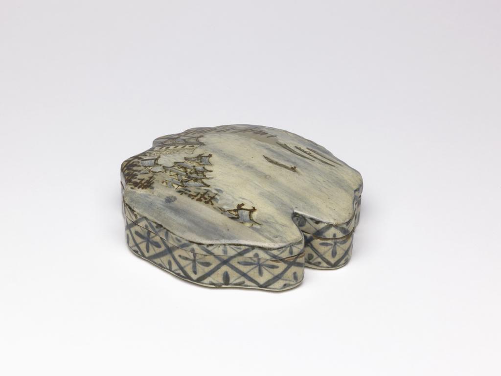 An image of Japanese pottery. Incense container with lid. Kenzan, pottery studio, Japan, Kyoto. Moulded stoneware base and lid of very irregular shape in pale grey clay. Decorated outside with creamy base glaze covered by scene of a castle by a lake with four boats, pine trees and house, in brown and blue. Inside, bands of gold and blue on a cream base, representing clouds. On sides, geometrical pattern in blue. Stoneware, glazed, height, base, 2.10 cm, diameter, rim, 11.00 cm, largest, diameter, base, 12.00 cm, largest, height, lid, 1.60 cm, diameter, lid, 12.10 cm, largest, height, overall, 2.40 cm, circa 1700- circa 1799. Edo Period (1615-1868).