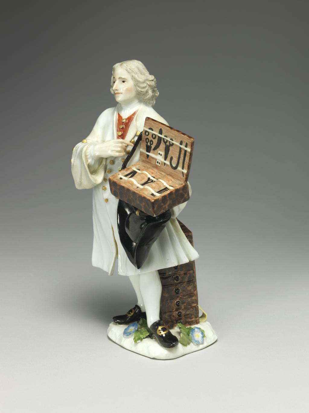 An image of A knife seller. Meissen Porcelain Manufactory. Kaendler, Johann Joachim, modeller, derived from (German, 1706-1775). Reinicke, Peter, modeller, derived from (German, 1715-1768). Hard-paste porcelain, press-moulded, and painted overglaze in enamels, and gilt. The flat underside is unglazed and has a small circular ventilation hole near the back. Height, whole, 18.7 cm, width, whole, 10 cm, depth, whole, 9 cm, circa 1745-1750. Production Note: This figure is Meissen model no. 965 which was modelled after 'Des Couteaux, des Cizeaux, des Peignes', the third print of the fourth set of prints entitled 'Études prises dans le bas Peuple ou les Cris de Paris' engraved by the comte de Caylus (1692-1765) after drawings by Edmé Bouchardon (1689-1762), and published in 1742. The figure's stance is transposed from the engraving.